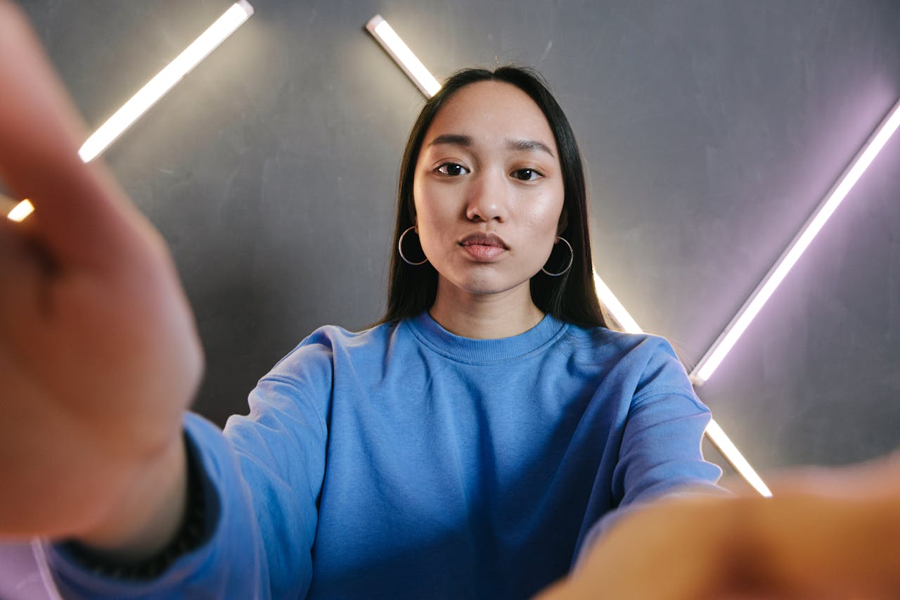 Asian woman in blue sweater streaming content in a modern room.