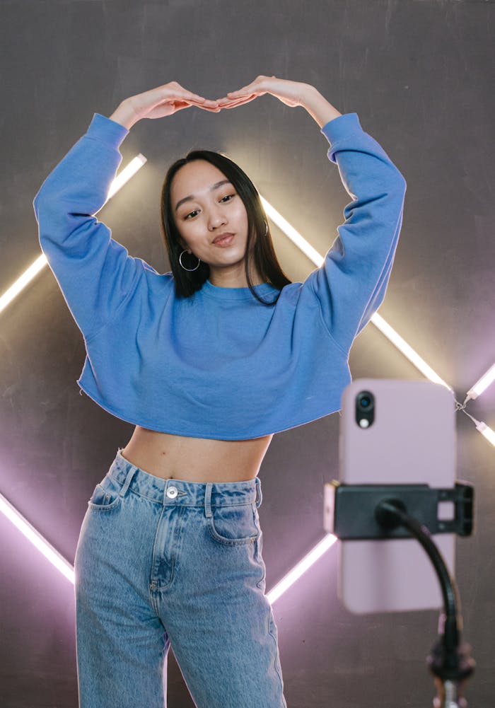 menu-01 Teenage influencer demonstrates dance moves in front of neon lights, filmed with a smartphone.